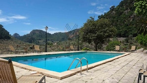 Una piscina con lettini, un lampione e montagne sullo sfondo.