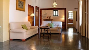 Un'ampia zona giorno con soffitto alto, travi in legno, due divani, un tavolino e una finestra che offre luce naturale.
