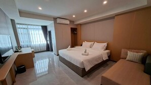 Una habitación de hotel moderna con una cama grande, un sofá, un televisor y un escritorio.