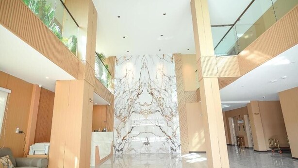 Un amplio vestíbulo con una recepción de mármol, techos altos y un atrio de cristal.