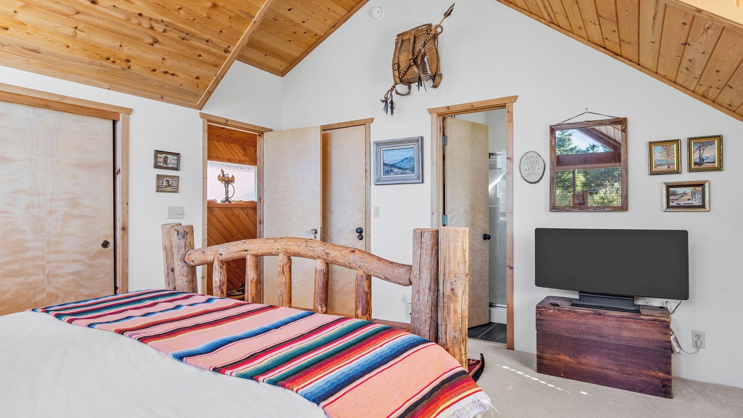 Un dormitorio con cama de madera, televisor y espejo.