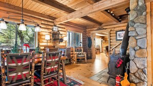 A log cabin interior with a stone fireplace, wooden furniture, and a cozy dining area.