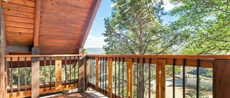 Una terraza de madera con vistas a árboles y montañas.