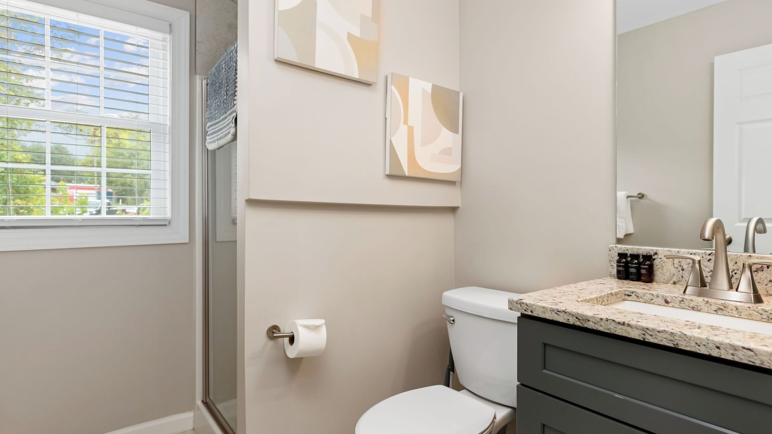 A bathroom with a toilet, sink, and window.