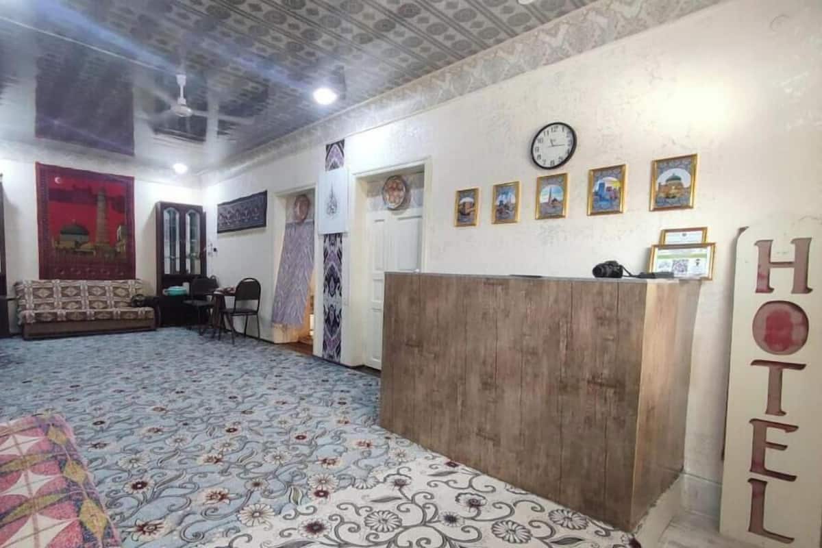 Zona de recepción de hotel con un escritorio de madera, un reloj y cuadros en la pared.