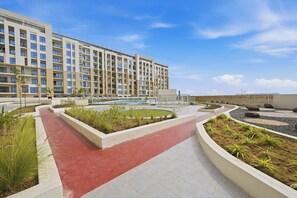 Ein modernes Hotel mit rotem Weg, angelegten Grünflächen und einem großen Gebäude im Hintergrund.
