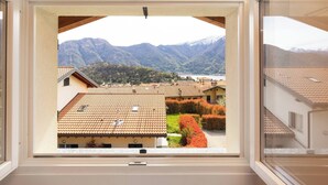 Blick aus dem Fenster auf eine Berglandschaft, im Vordergrund befinden sich Gebäude.