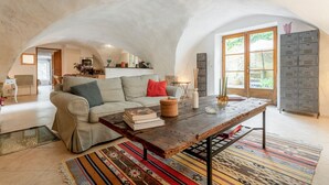 A cozy living room with a sofa, coffee table, and books. - 2-person gîte with Gardoise vault in a restored 16th-century mas, 15 km from Uzès (Lussan)