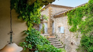 A stone building with a staircase, a hanging light fixture, and greenery.