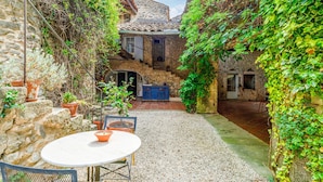 A courtyard with a stone wall, a table with chairs, and a blue cabinet.