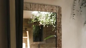 A bathroom with a mirror, a shelf with towels and toiletries, and a view of a wooden interior. - Tulus Hati Ubud Retreat (Ubud)