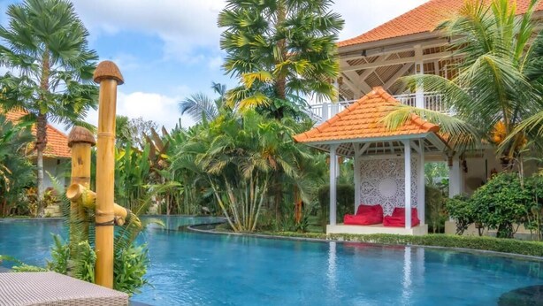 A pool area with a gazebo, palm trees, and a building with a tiled roof. - Tulus Hati Ubud Retreat (Ubud)