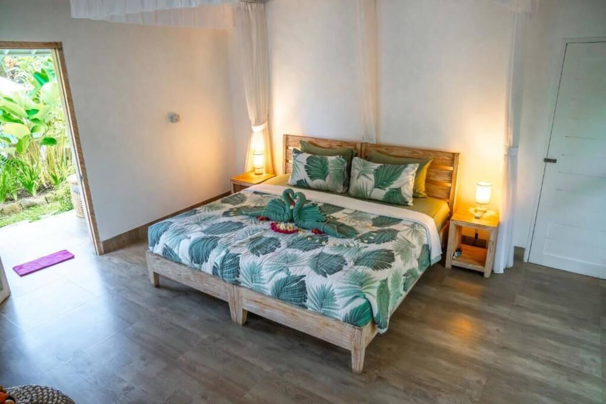 A bedroom with a bed, two bedside tables, a window with curtains, and a door.