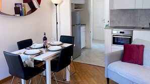 Une cuisine moderne dotée d’un four encastré et d’un coin repas avec une table dressée pour deux personnes.