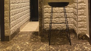 A modern interior with a stone-textured wall, a black and yellow cabinet, a black bar stool, and a marble floor. - Citistay Apartments (Abuja)