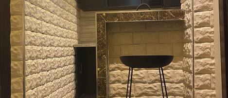 A modern interior with a stone-textured wall, a black and yellow cabinet, a black bar stool, and a marble floor.