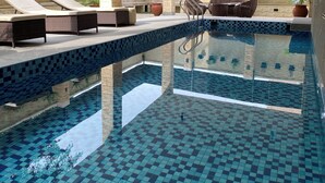 A swimming pool with tiled flooring, lounge chairs, and potted plants. - Citistay Apartments (Abuja)