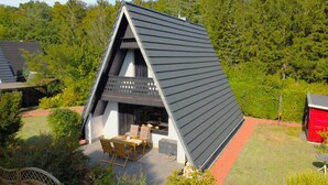 Een modern, driehoekig gebouw met een overdekte patio, compleet met tuinmeubilair.