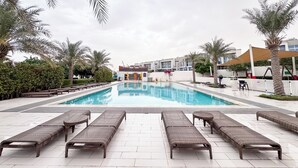 Ein Schwimmbecken mit Liegestühlen und einem Gebäude im Hintergrund.