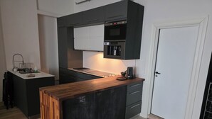 Uma cozinha moderna com ilha central, armários escuros e forno embutido.