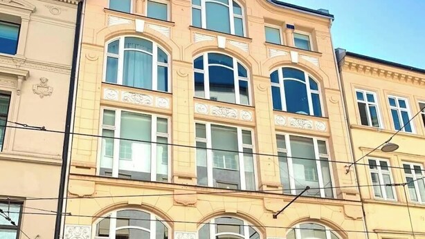 Um edifício de vários andares com estilo arquitetônico clássico, apresentando janelas em arco e molduras decorativas.