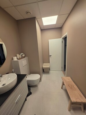 Ein Badezimmer mit Waschbecken, Toilette und Sitzbank.