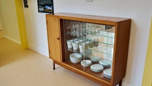 A wooden cabinet with glass doors containing plates, bowls, and cups.