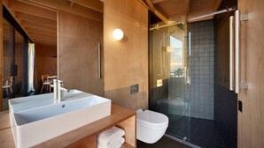 A modern bathroom with a large bathtub, a glass-enclosed shower, and a wooden vanity.