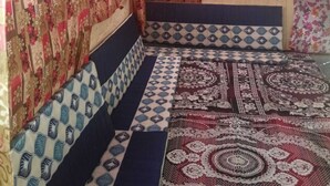 A room with a patterned bedspread, a patterned wall, and a patterned ceiling. - River View Cafe & Camping (Jibhi)