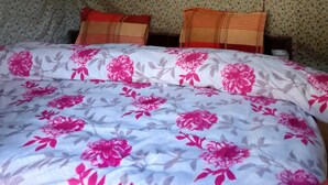 A tent-style room with a bed, two pillows, and a small window. - River View Cafe & Camping (Jibhi)