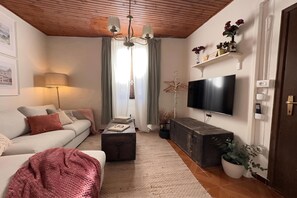 A living room with a sofa, a coffee table, a TV, and a wooden ceiling.