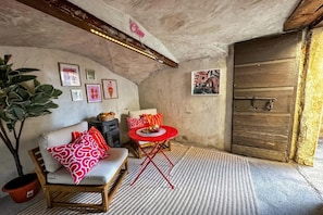 A cozy room with a wooden bench, a red table, and a large potted plant.