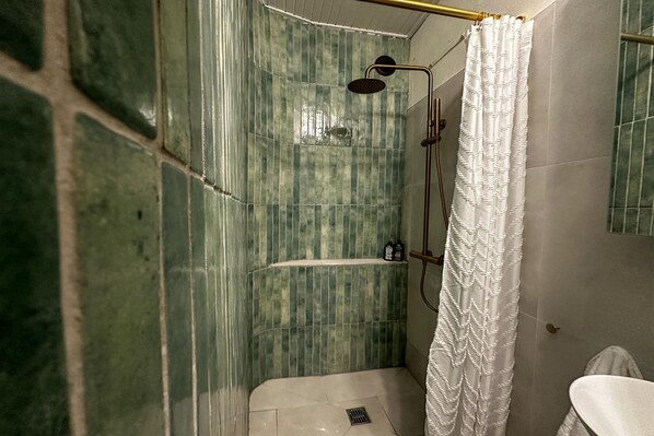Une salle de bain avec une douche, des toilettes et un miroir.
