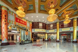 Un hall d’entrée spacieux, agrémenté d’éléments architecturaux traditionnels chinois, notamment des colonnes richement décorées et des lanternes suspendues.