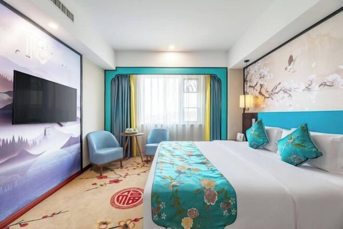 Quarto de hotel com uma cama, televisão, escrivaninha e uma cadeira.
