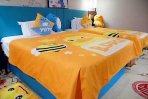 Une chambre d’hôtel avec deux lits, chacun recouvert d’une couverture orange ornée de personnages de dessins animés.