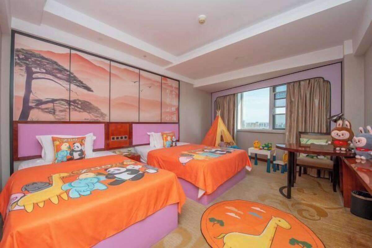 Quarto de hotel com duas camas, uma escrivaninha, uma cadeira, uma janela com cortinas e um quadro grande na parede.