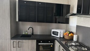Ett modernt kök med inbyggd ugn, mikrovågsugn, gasspis och diskho.