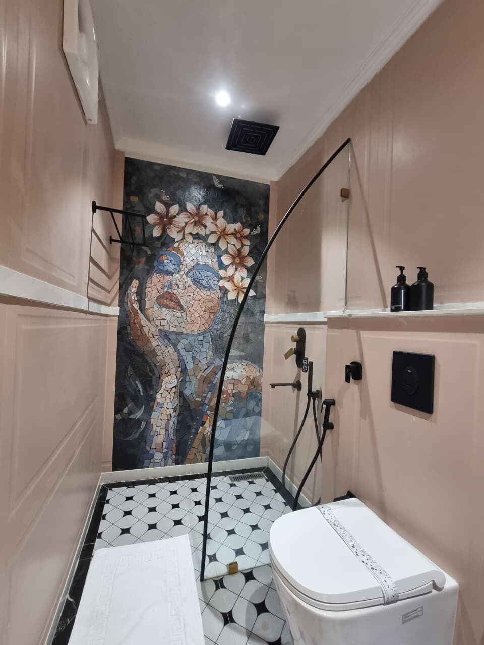 Un baño con pared de mosaicos, inodoro, lavabo y zona de ducha.