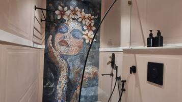 Un baño con pared de mosaicos, inodoro, lavabo y zona de ducha.