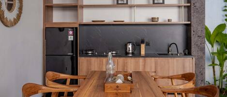 A wooden dining table with chairs, a kitchen with wooden cabinets, and a refrigerator.