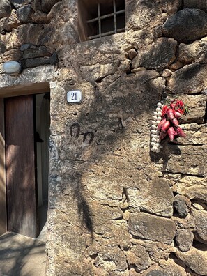 A stone wall with a number sign, a wooden door, and a cluster of red chili peppers. - ANCIENT RURAL DAMMUSO WITH POOL AND SEA VIEW (Pantelleria)