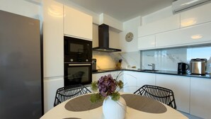 Een moderne keuken met witte kasten, een zwarte afzuigkap, een magnetron en een klok aan de muur.