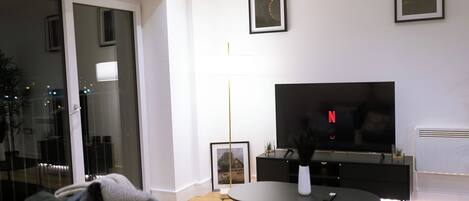 A modern living room with a large flat-screen TV, a sofa, a coffee table, and a framed picture on the wall.