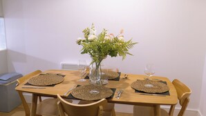 Ein Esstisch gedeckt mit Platzsets, Besteck und einer Vase mit Blumen.