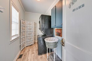 A laundry room with a washing machine, a drying rack, and a metal bucket on a stool. - Modern Farmhouse Retreat in the Crouse Countryside (Crouse)