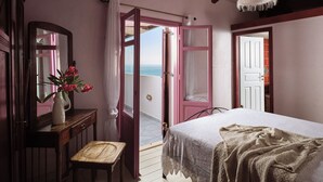 A bedroom with a bed, a chair, a dresser, a mirror, and a view of the sea through an open door. - Villa Yiannis - Sea View & Private Pool (Zakynthos)