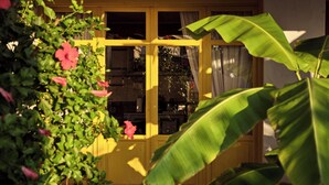 A yellow-framed window with a view of indoor plants and a door. - Villa Yiannis - Sea View & Private Pool (Zakynthos)
