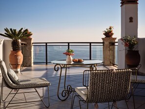 A terrace with a round table, two chairs, potted plants, and a view of the sea. - Villa Yiannis - Sea View & Private Pool (Zakynthos)