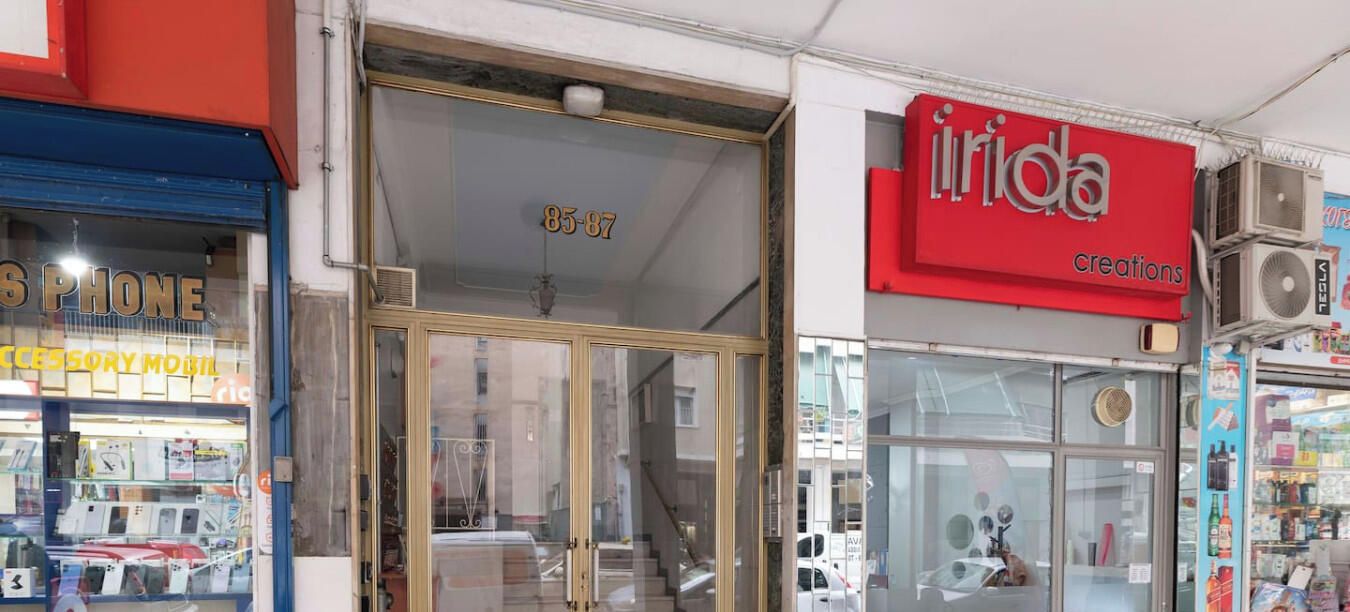 Une devanture de magasin avec une porte vitrée, une enseigne rouge sur laquelle on peut lire « Irida Creations », et des unités de climatisation fixées au mur.